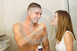 Handsome man putting cream on girlfriends nose