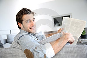 Handsome man reading newspaper in sofa