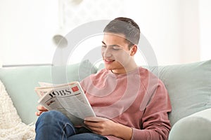 Handsome man reading newspaper on sofa at home