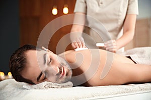 Handsome man receiving hot stone massage