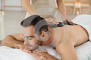 Handsome man receiving hot stone massage