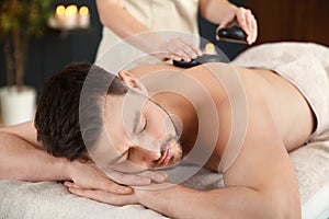 Handsome man receiving hot stone massage