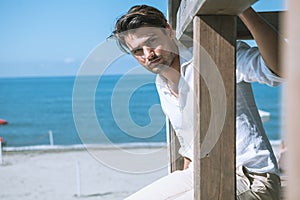 Handsome man relaxed at the sea, overlooking a wooden structure. Sea and blue sky.