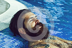Handsome man relaxes in pool on blue water background