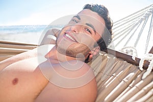 Handsome man relaxing in the hammock and smiling at camera