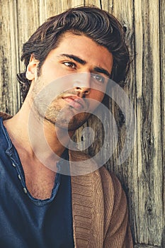 Handsome man relaxing leaning to a wooden wall