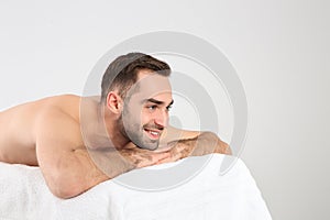 Handsome man relaxing on massage table against white