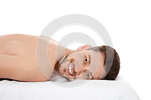 Handsome man relaxing on massage table against white background