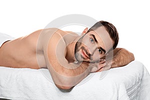 Handsome man relaxing on massage table against white background