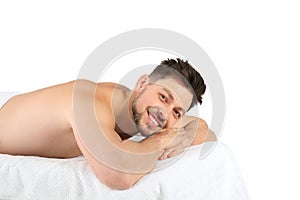 Handsome man relaxing on massage table against white background