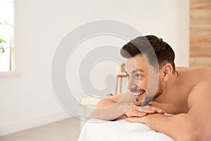 Handsome man relaxing on massage table in spa salon