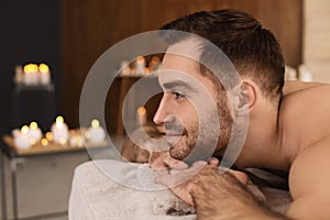Handsome man relaxing on massage table in spa salon