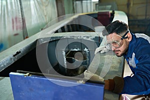 Handsome man repairing boat in workshop