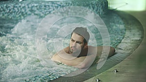 Handsome man resting in jacuzzi spa. Sexy man relaxing in whirlpool bath