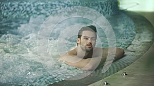 Handsome man resting in jacuzzi spa. Sexy man relaxing in whirlpool bath