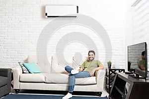 Handsome Man Resting On Sofa Below Air Conditioner