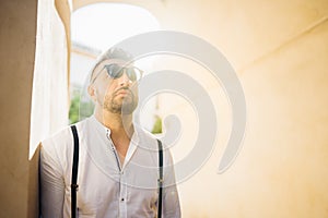 Handsome man with round glasses and beard standing in sunset light.Portrait of good looking guy.Male tourist