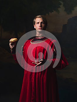 Handsome man in a Royal red doublet eating fast food.