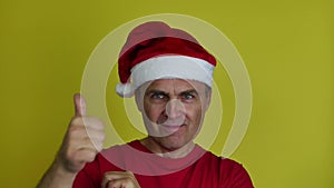 A handsome man in a Santa Claus hat expresses his emotions with hand gestures.