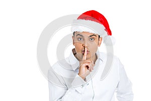 Handsome man in santa claus hat with his finger on lips