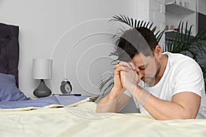 Handsome man saying bedtime prayer at home