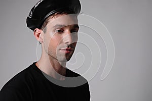 Handsome man with serious face expression wears black hat over white background. photo
