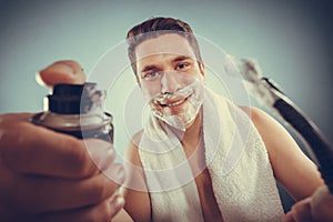 Handsome man with shaving cream foam can and razor