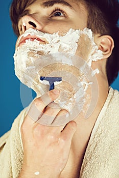 Handsome man shaving hair on neck with safety razor