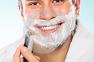 Handsome man shaving with razor