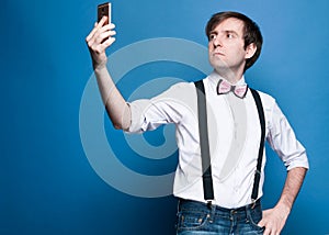 handsome man in shirt with rolled up sleeves and black suspender standing and taking selfie