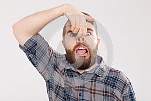 Handsome man shows crazy silly grimace or facial expression, isolated on white background. Making funny emotion on face