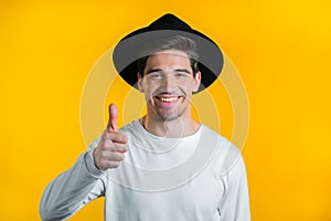 Handsome man shows thumbs up, Like gesture. Happy guy on yellow background. Winner. Success. Positive male model smiles