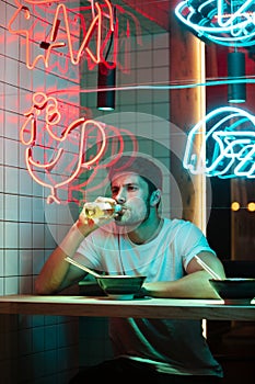 Handsome man sitting in cafe looking aside eating.