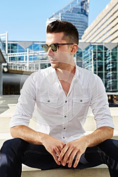 Handsome man sitting in city with sunglasses