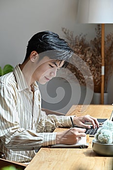 Handsome man sitting in coffee shop and working online with laptop.