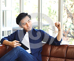 Handsome man sitting on couch in living room ,showing pinkie or little  finger for reconcile gesture