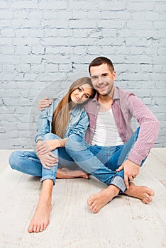 Handsome man sitting on the floor and embracing his girlfriend