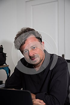 Handsome man sitting in his forties with blue eyes at home living interior room home