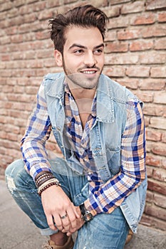 Handsome man sitting near a brick wall