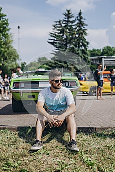 Handsome man sitting near muscle car. Green machine