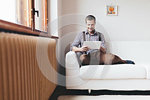 Handsome man sitting on sofa using a digital tablet