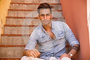 Handsome man sitting on stairs while looking at camera