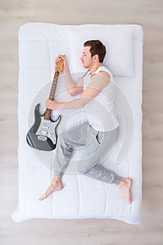 Handsome man sleeping with guitar