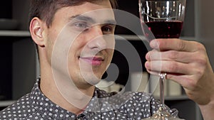 Handsome man smelling delicious red wine, relaxing at home