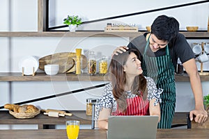 Handsome man is smiling and touching beautiful woman's head while she working on computer laptop.