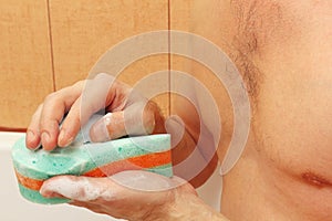 Handsome man soaping green sponge with soap