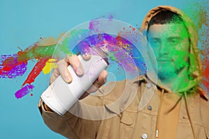 Handsome man spaying paint against light blue background