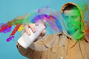 Handsome man spaying paint against light blue background photo