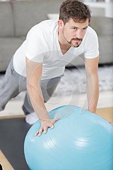 Handsome man in sportswear holding plank with fitball