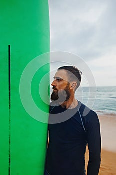 Handsome man stand with long surf surfing board wait on surf spot at sea ocean beach.